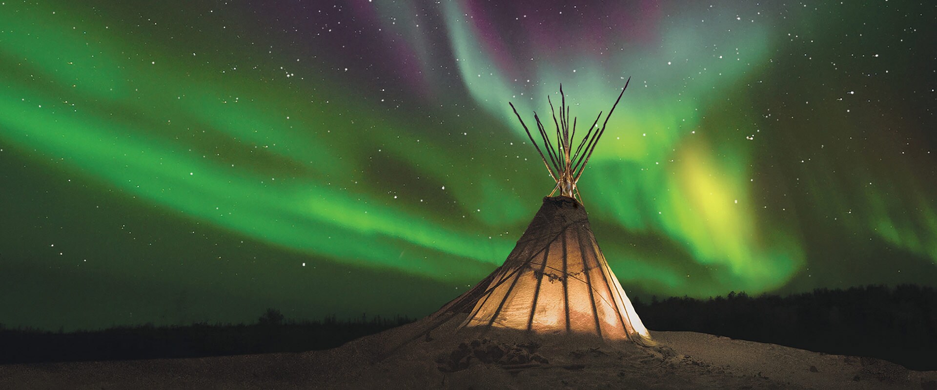 Teepee lit up under the Northern Lights