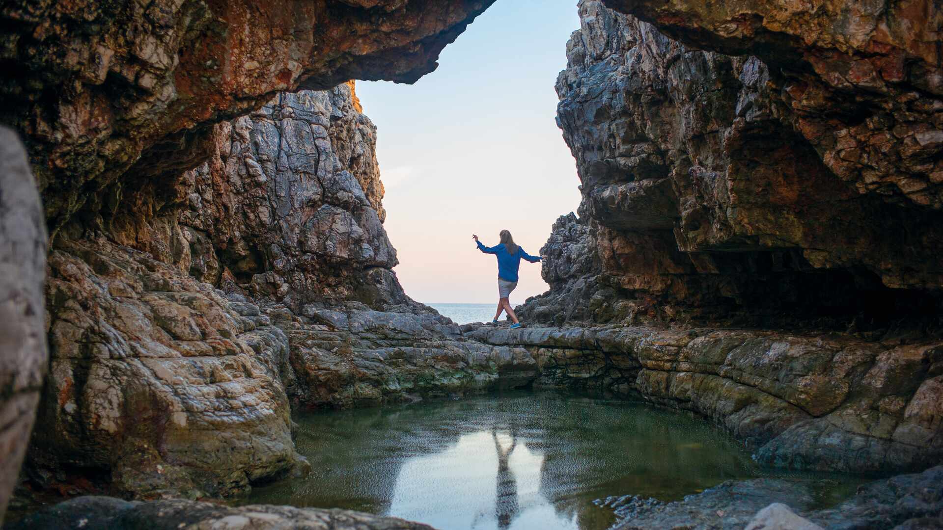 Woman walking through rock cave, Croatia